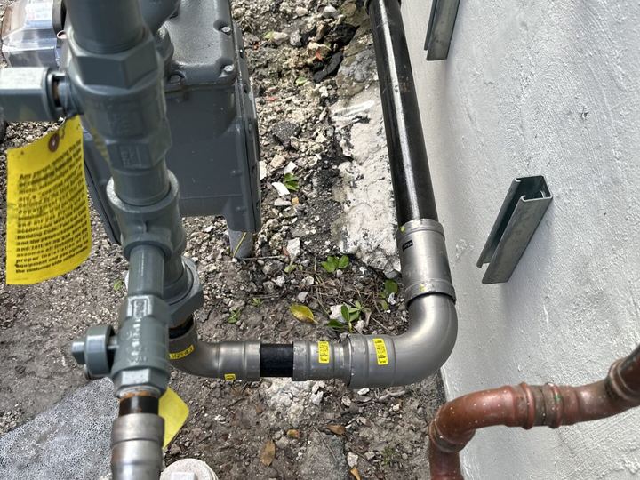 Exterior supply and gas piping on a Miami stucco wall