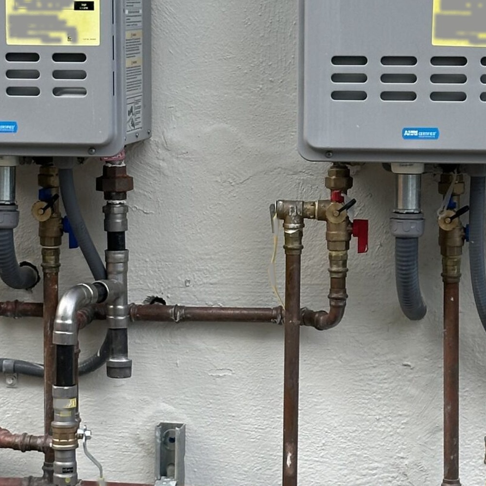 Dual outdoor tankless water heaters mounted on Miami stucco